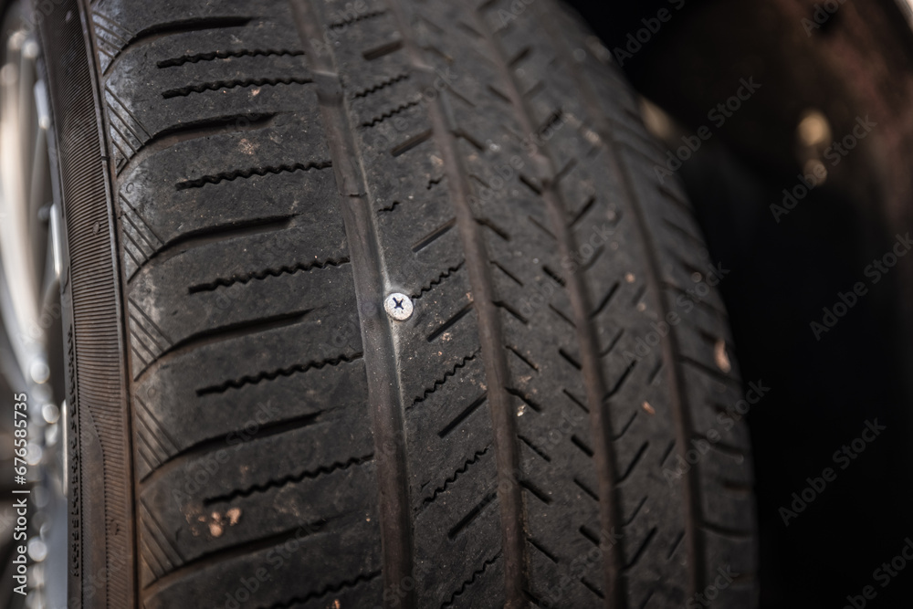 A screw stuck in a car tire puncturing it and making it flat A screw stuck in a car tire puncturing it and making it flat