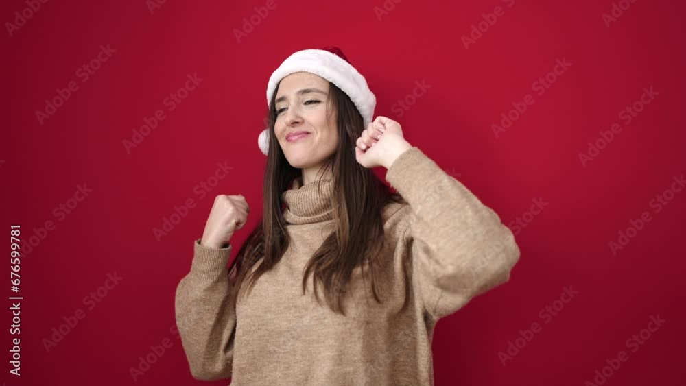 Beautiful hispanic woman smiling confident wearing christmas hat dancing over isolated red background Beautiful hispanic woman smiling confident wearing christmas hat dancing over isolated red background