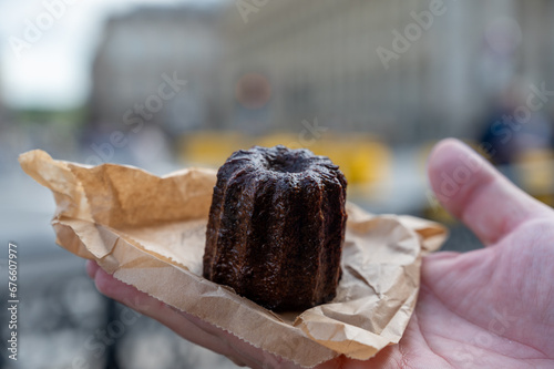 Fototapeta Naklejka Na Ścianę i Meble -  Canele, French pastry flavored with rum and vanilla, soft and tender custard center and  dark, caramelized crust specialty of Bordeaux region, France, streets of Bordeaux on background