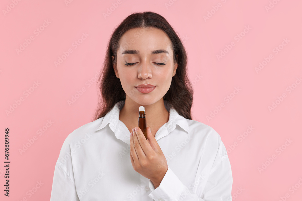 Beautiful young woman with bottle of essential oil on pink background Beautiful young woman with bottle of essential oil on pink background