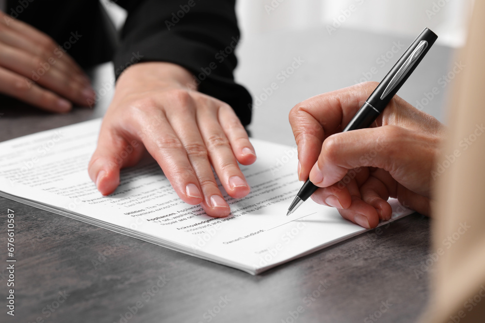 Manager showing client where she must to mark signature at dark table, closeup Manager showing client where she must to mark signature at dark table, closeup