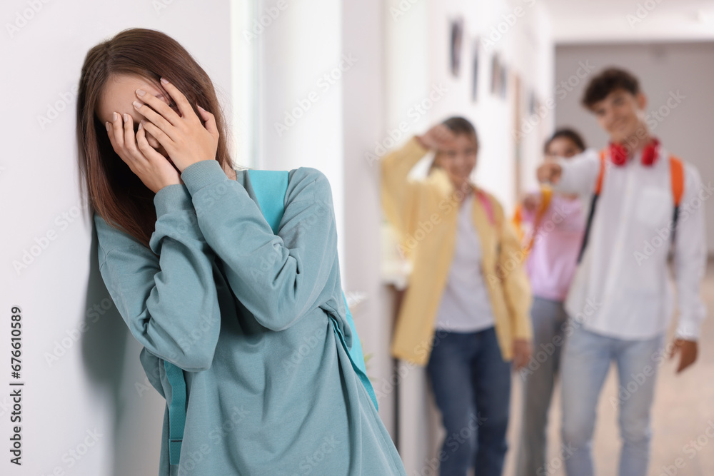 Teen problems. Lonely girl standing separately from other students at school Teen problems. Lonely girl standing separately from other students at school