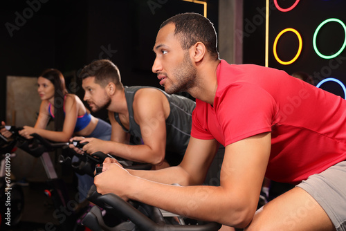 Group of people training on exercise bikes in fitness club