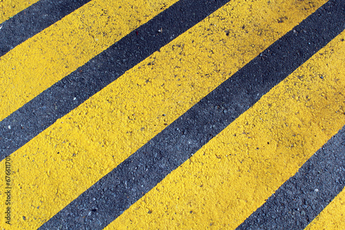 Yellow parallel hazard lines painted on asphalt road © Tammy