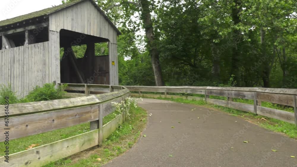 Black covered bridge in Prebble County Ohio. Shot is a pan from right to left, starting with the approach road and ending with the full bridge. Shot on an overcast afternoon. Black covered bridge in Prebble County Ohio. Shot is a pan from right to left, starting with the approach road and ending with the full bridge. Shot on an overcast afternoon.