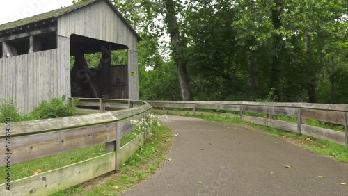 Black covered bridge in Prebble County Ohio. Shot is a pan from right to left, starting with the approach road and ending with the full bridge. Shot on an overcast afternoon. photo