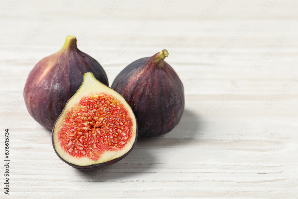Whole and cut ripe figs on white wooden table, closeup. Space for text Whole and cut ripe figs on white wooden table, closeup. Space for text