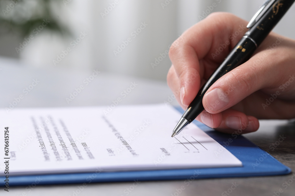 Woman signing document at dark table indoors, closeup. Space for text Woman signing document at dark table indoors, closeup. Space for text