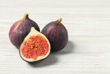 Whole and cut ripe figs on white wooden table, closeup. Space for text