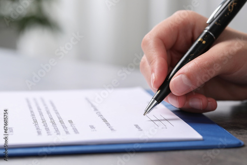 Woman signing document at dark table indoors, closeup. Space for text © New Africa