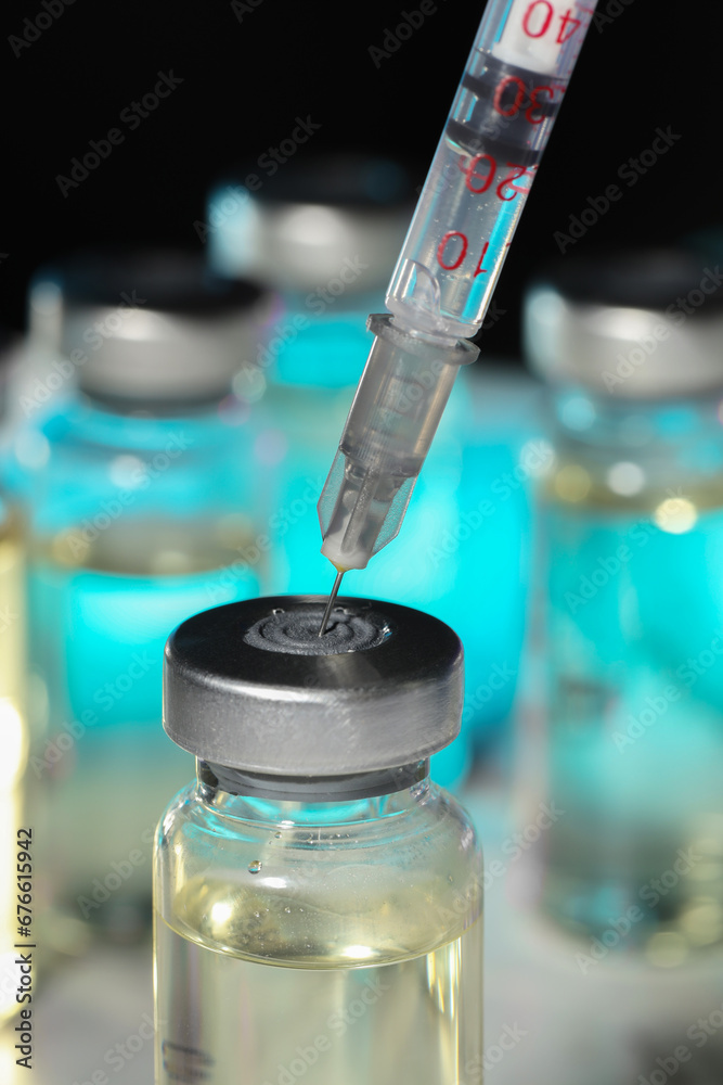 Filling syringe with medicine from vial against blurred background, closeup Filling syringe with medicine from vial against blurred background, closeup
