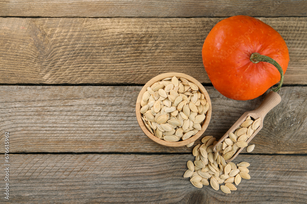 Bowl, scoop with seeds and fresh pumpkin on wooden table, flat lay. Space for text Bowl, scoop with seeds and fresh pumpkin on wooden table, flat lay. Space for text