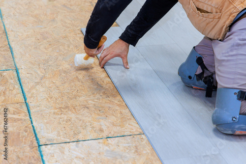 An installation worker installs vinyl laminate flooring in new home