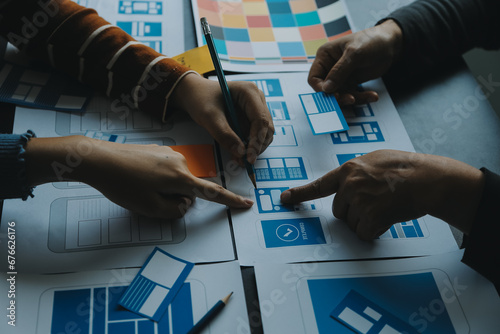 Close up ux developer and ui designer brainstorming about mobile app interface wireframe design on table with customer breif and color code at modern office.Creative digital development agency photo