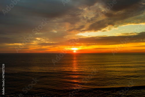 During early morning hours, sun rises over waves ocean
