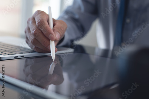Businessman, manager using stylus pen signing e-document on digital tablet with laptop computer on table at modern office, e-signing, electronic signature, paperless office, digital document concept