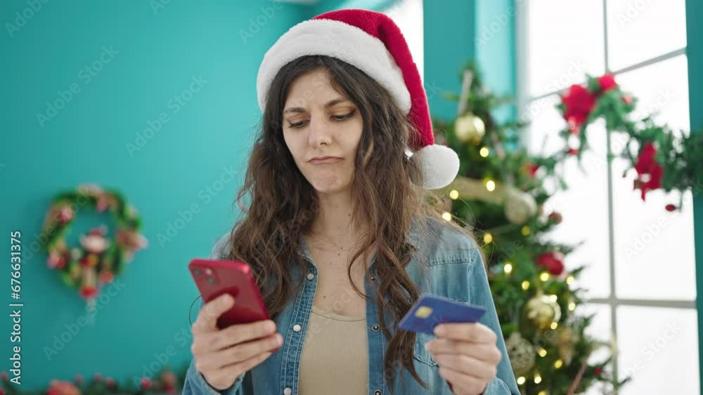 Young beautiful hispanic woman shopping with smartphone and credit card celebrating christmas at home Young beautiful hispanic woman shopping with smartphone and credit card celebrating christmas at home