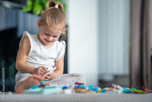 Smiling Little girl playing with small constructor toy on the floor in home living room, educational game, spending leisure activities time concept