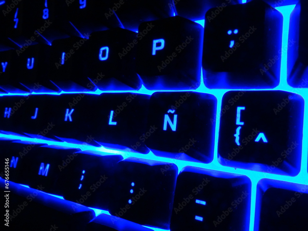 Backlight gaming keyboard desktop with RGB blue light glow in the dark. Close-up ñ key Backlight gaming keyboard desktop with RGB blue light glow in the dark. Close-up ñ key