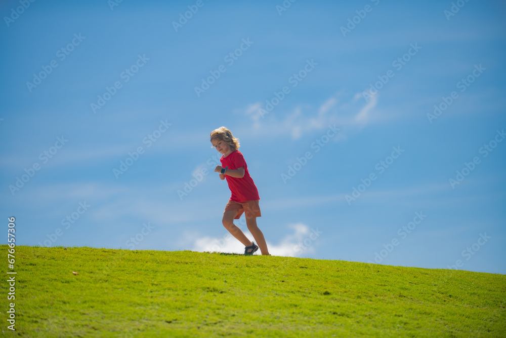 Cute boy running on green grass and blue sky. Run and healthy sport for children. Child running on summer park. Running training outdoor. Children athletes. Cute boy running on green grass and blue sky. Run and healthy sport for children. Child running on summer park. Running training outdoor. Children athletes.