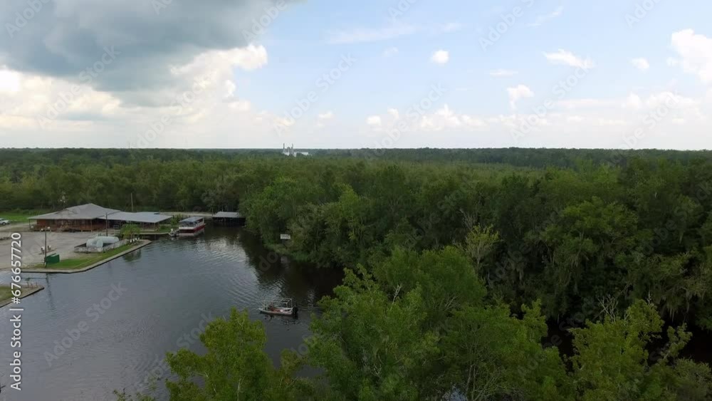 Aerial Shot Of Nautical Vessel Floating In Rippled River, Drone Flying Forward Over Green Trees Under Clouds - Bayou, Louisiana