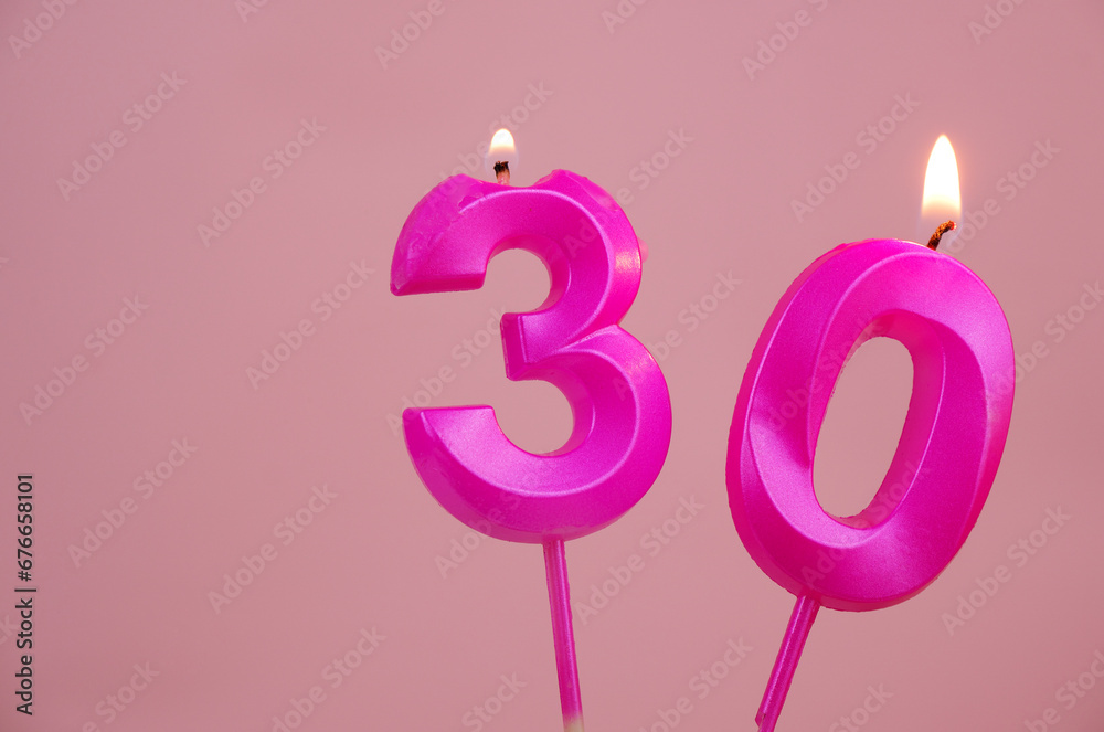 Pink birthday candles burning and melting on pink background. Copy space for text. Number 30.