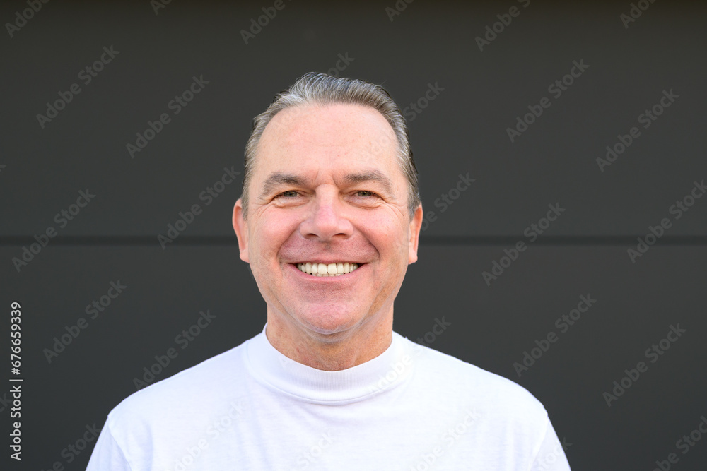 A man in a white turtle neck t shirt giving a very big smile to the camera A man in a white turtle neck t shirt giving a very big smile to the camera
