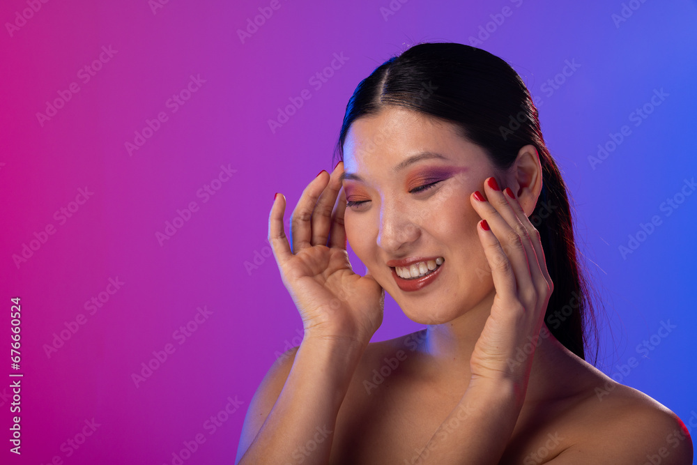 Asian woman wearing purple eye shadow and red nail polish on purple background, copy space Asian woman wearing purple eye shadow and red nail polish on purple background, copy space