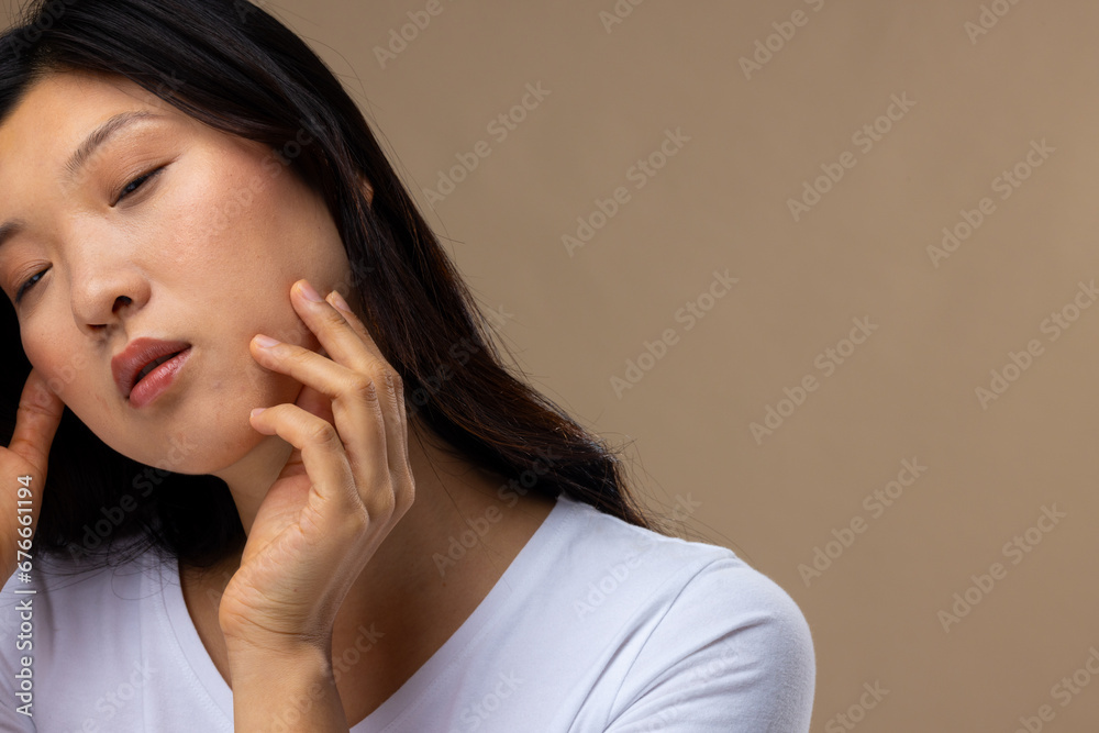 Asian woman wearing natural makeup and white t-shirt on beige background, copy space Asian woman wearing natural makeup and white t-shirt on beige background, copy space