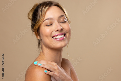 Caucasian woman wearing natural makeup and blue nail polish on beige background, copy space photo