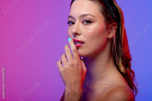 Portrait of caucasian woman wearing blue nail polish on purple background, copy space
