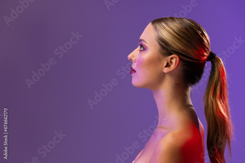 Caucasian woman wearing red lipstick and blue nail polish on purple background, copy space