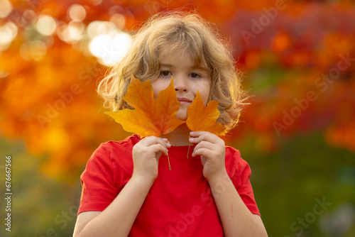 Autumn Kid Portrait In Fall Yellow Leaves. Little Child In in Park Outdoor  Autumn Clothing for October Season. Closeup kids face on sunset in autumn light. Autumn portrait of excited surprised kid.