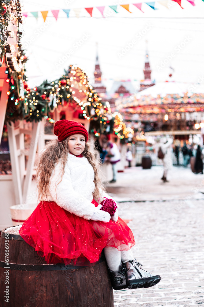 girl in a white fur coat and a red hat and skirt next to Christmas Tree have fun on Red Square in Moscow during the Christmas and New Year holidays at a festive fair, Gifts for Christmas and New Year