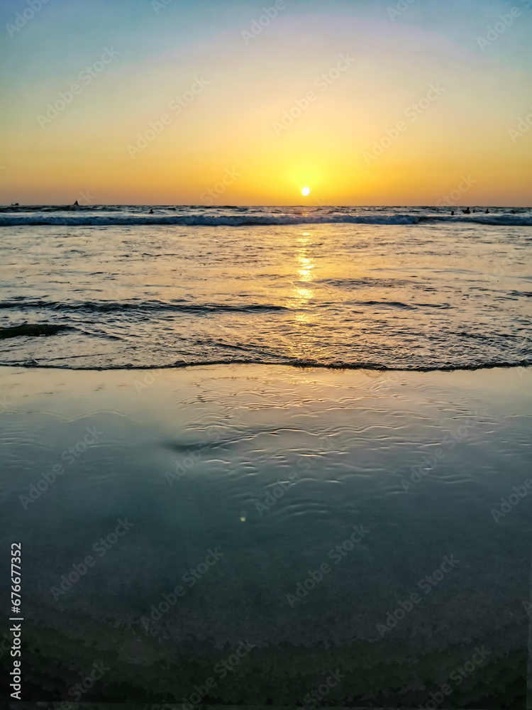 Sunset on Mandrem Beach in Goa, India. Bright and colorful sunset over the Indian Ocean, the Arabian Sea. A tropical beach with yellow sand and a bronze sunset.