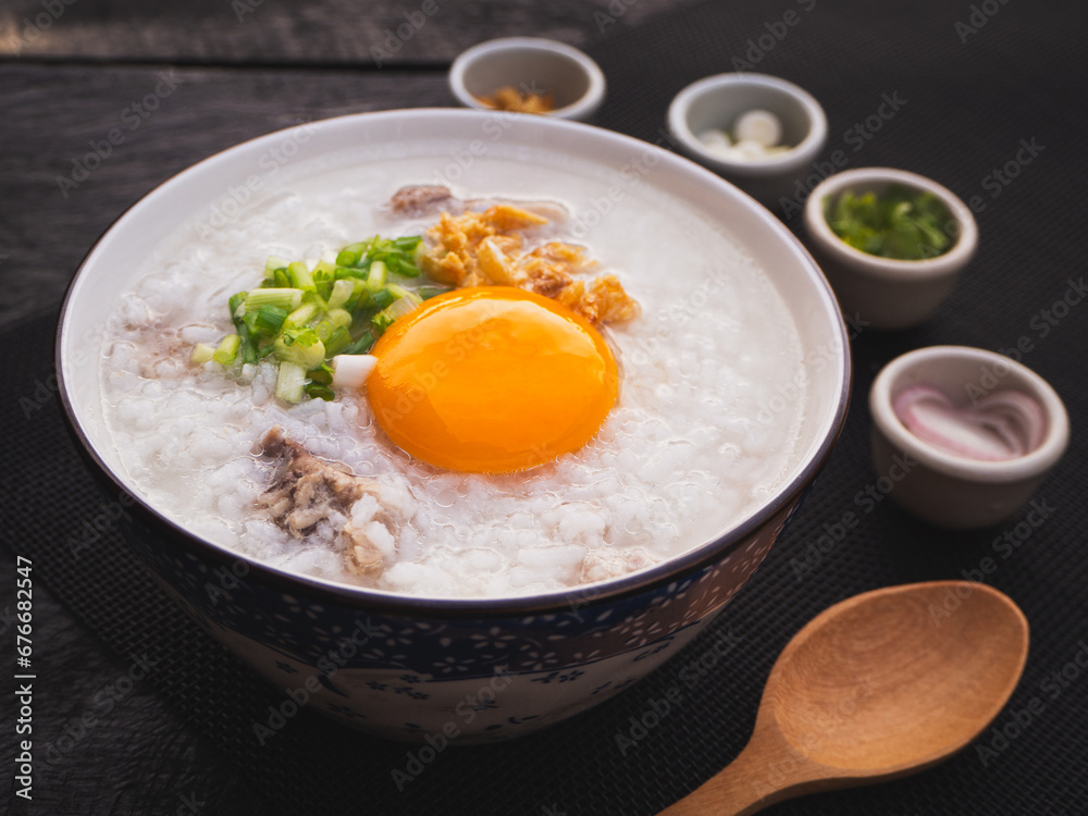 Rice soup or boiled rice with pork ribs and egg in bowl on wooden table background. Thai Food Rice soup or boiled rice with pork ribs and egg in bowl on wooden table background. Thai Food