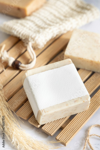 Beige handmade soap bar with blank label on wooden tray close up, mockup