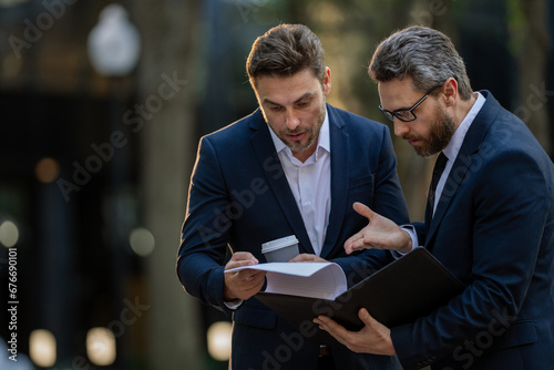 Business discussion. Businessman sharing his experience. Business partners meeting outdoor. Two confident business people in formalwear discussing something while sitting at the street.