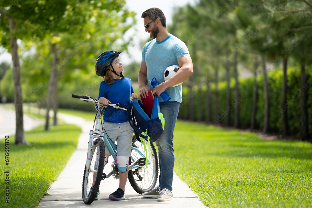 Obraz premium Happy fathers day. Father helping son get ready for school. Father and son riding bike in american neighborhood. Parents and children friends. Child first bike.