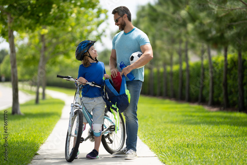 Happy fathers day. Father helping son get ready for school. Father and son riding bike in american neighborhood. Parents and children friends. Child first bike.