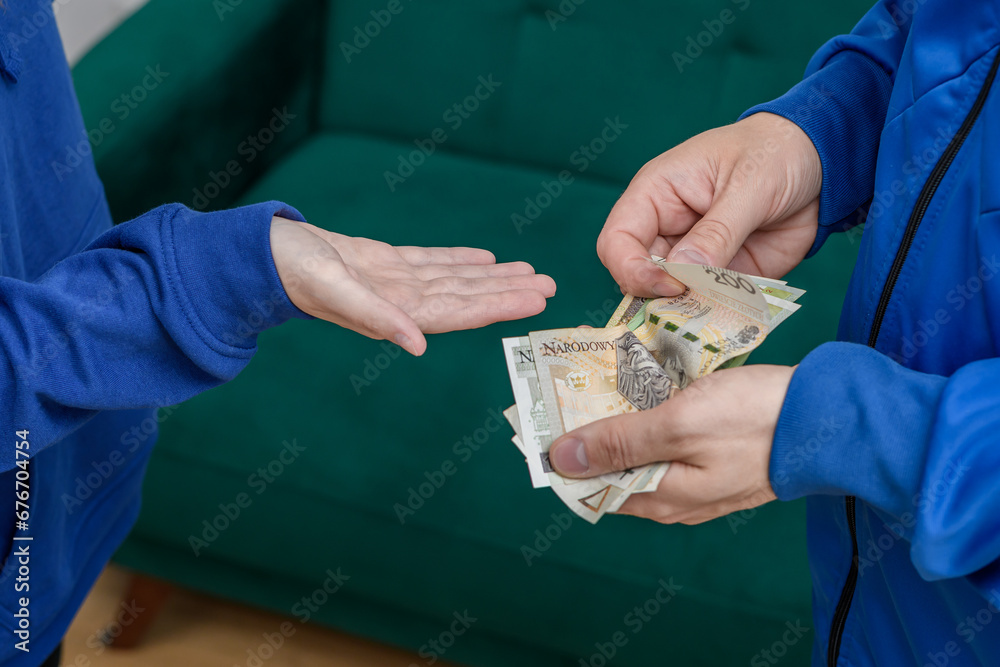 Kobieta wyciąga dłoń po pieniądze, mężczyzna płaci polską gotówką - obrazy, fototapety, plakaty 