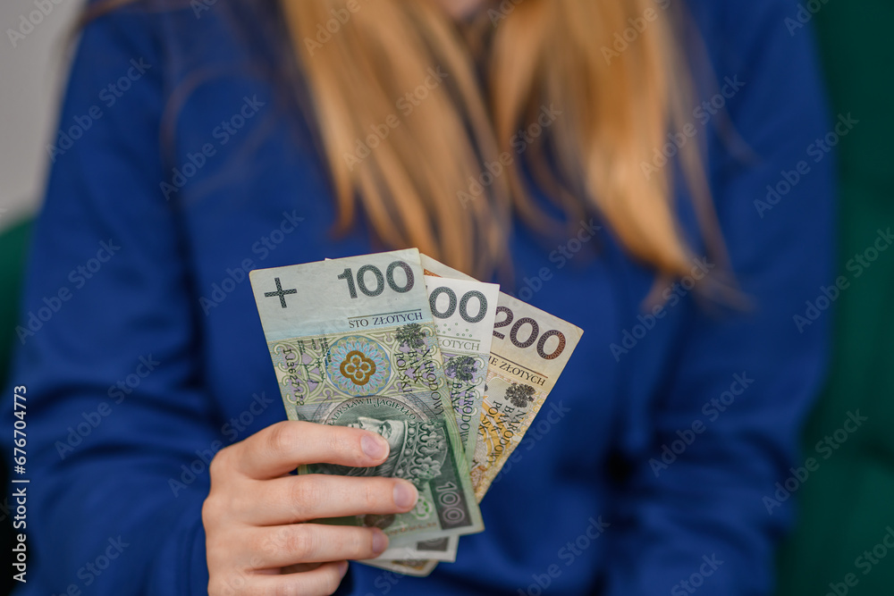 Kobieta trzyma wachlarz polskich banknotów PLN w dłoni - obrazy, fototapety, plakaty 