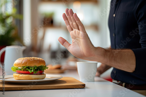 Close-up of male hand showing stop gesture to cheeseburger