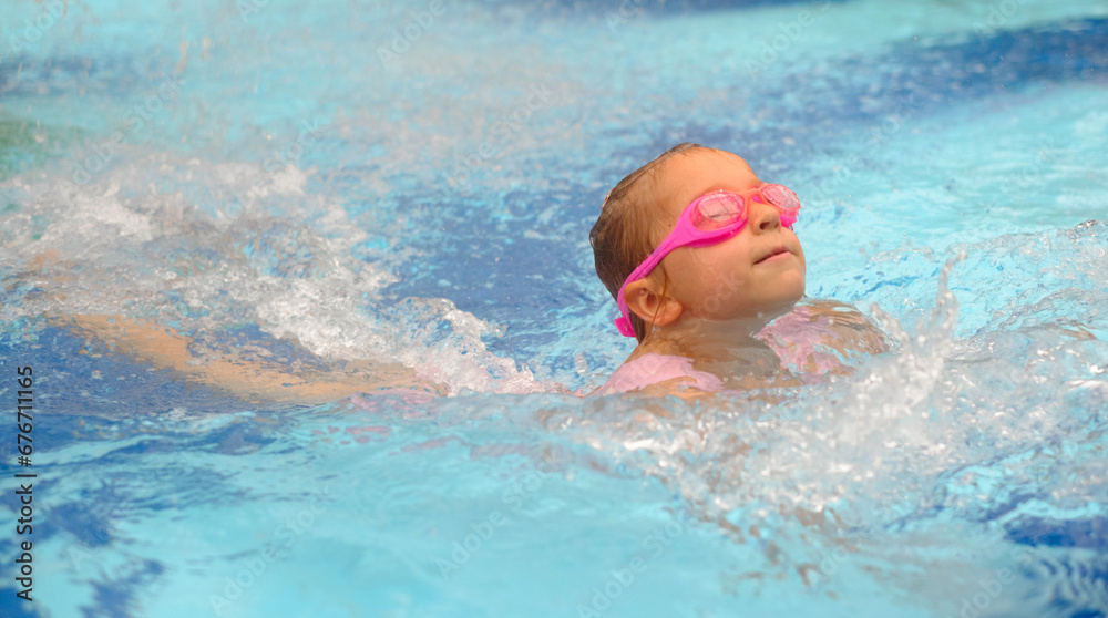 Child diving in swimming pool. Toddler kid jumping into the water in goggles learning to swim. Girl having fun in water, splashing in aquapark