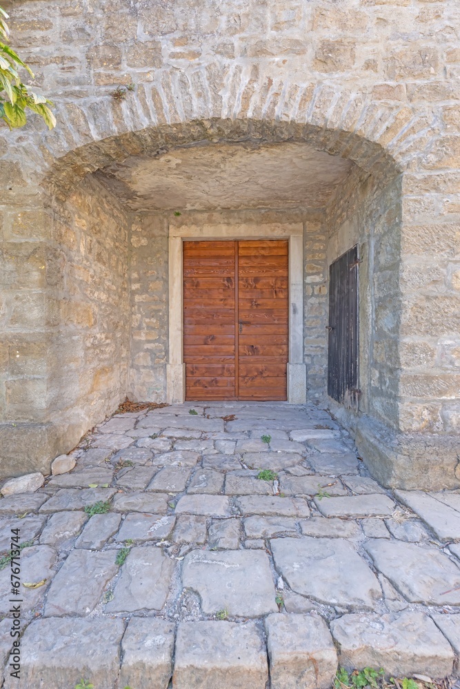 Fototapeta premium Image of a redbrown entrance door to a residential building with an antique façade