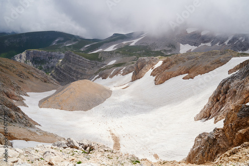 A breathtaking view of a mountain gorge with a melted glacier inside.