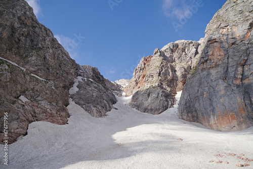 A glacier lying in a rocky gorge lit by the midday sun in summer.