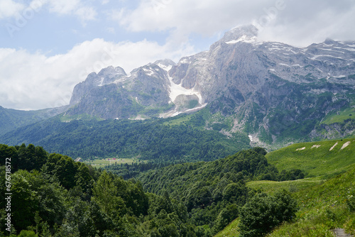 Spectacular mountain landscape with green forests and snowy peaks.