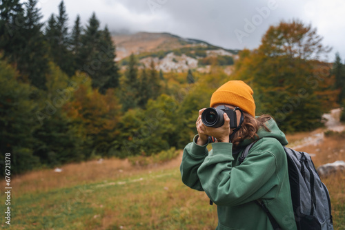 Obraz na płótnie Woman traveler photographer taking photo using camera during autumn trip to mountains w salonie