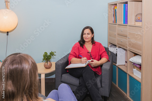 Woman psychotherapist listening attentively to her adolescent patient in therapy session. Concept of accompaniment and mental health